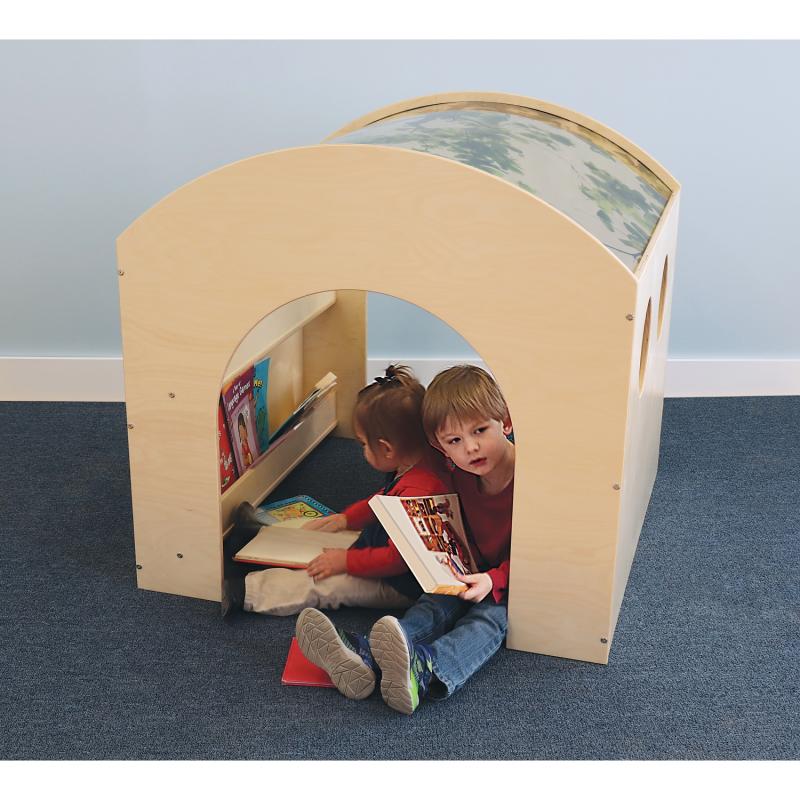 Children reading books inside a wooden playhouse with a blue carpeted floor and light blue wall.