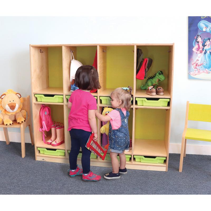 Two young children standing in front of a light wood toy organizer cubby shelf with green drawer bins in a children's room.